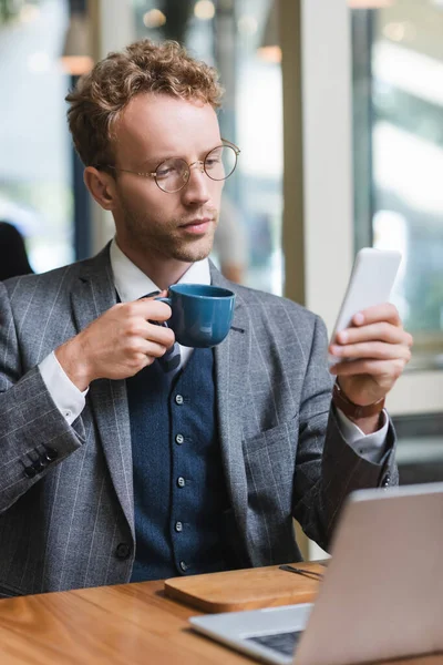 Krullende Zakenman Bril Met Behulp Van Mobiele Telefoon Holding Cup — Stockfoto