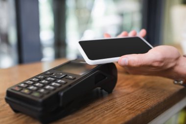 Kafede akıllı telefonla ödeme yapan bir adamın görüntüsü. 