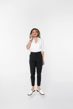 Mutlu Afro-Amerikan iş kadını kameraya bakıyor ve cep telefonundan arıyor.