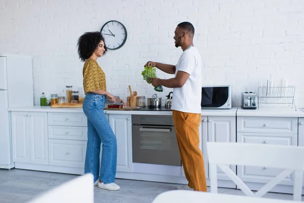 Side View African American Man Holding Lettuce Smiling Girlfriend Kitchen — Stock Photo, Image