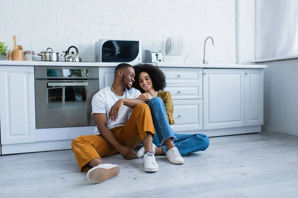 African American Man Sitting Smiling Girlfriend Floor Kitchen — ストック写真