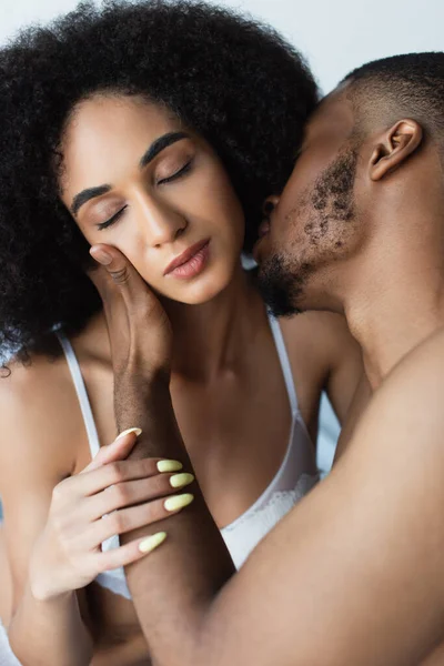 Young african american man kissing and touching sensual girlfriend in bra