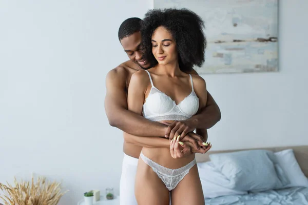 Sorrindo Homem Abraçando Sensual Afro Americano Namorada Quarto — Fotografia de Stock