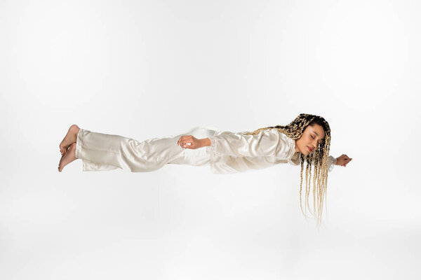 Африканская американка в шелковой пижаме, летящая во сне изолированная на белом