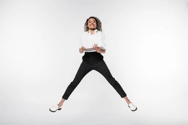 Young African American Businesswoman Smiling Camera While Levitating Laptop Isolated — Stock Photo, Image