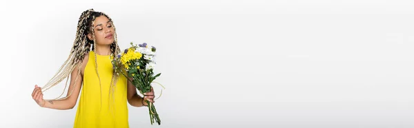 Sonriente Mujer Afroamericana Sosteniendo Flores Brillantes Mientras Toca Cabello Aislado — Foto de Stock