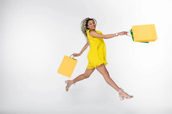 Excited African American Woman Yellow Dress Levitating Shopping Bags Isolated — Stock Photo, Image