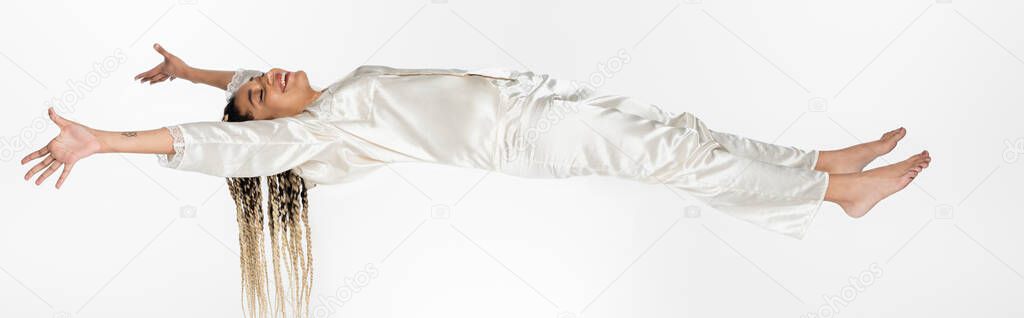 young african american woman smiling while flying in dream isolated on white, banner