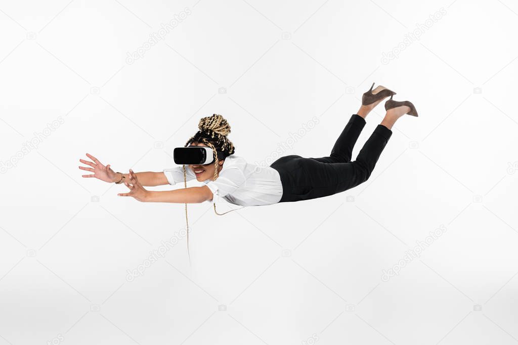 cheerful african american businesswoman levitating in vr headset isolated on white 