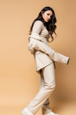 Balıkçı yaka ve takım elbiseli genç model bej rengi poz veriyor.