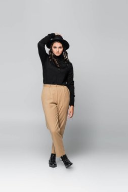 Siyah fötr şapkalı ve gri elbiseli genç bir model.