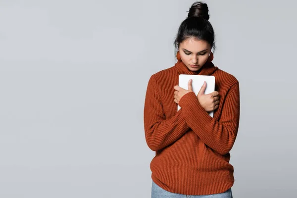 穿着保暖毛衣的年轻女子拿着用灰色隔离的数码平板电脑 — 图库照片