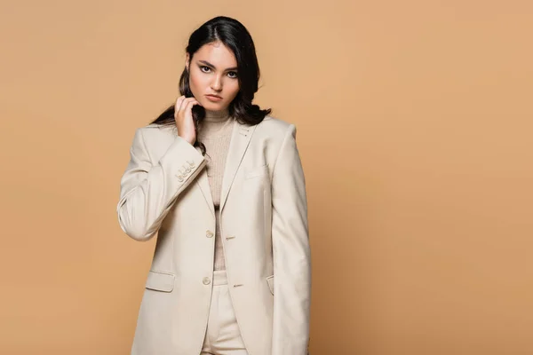 Brunette Jonge Vrouw Trendy Pak Aanpassen Haar Geïsoleerd Beige — Stockfoto