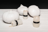 white halloween pumpkins near burning candles isolated on black 