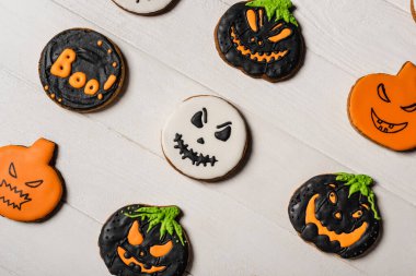top view of sweet and spooky pumpkin shape halloween cookies on white surface clipart