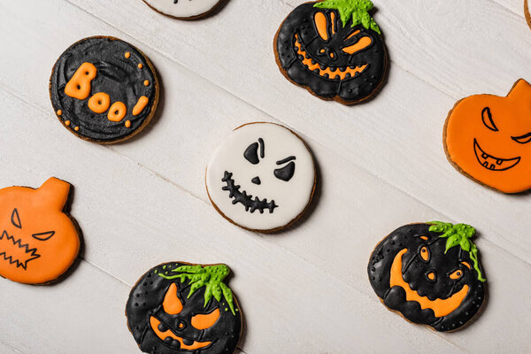 top view of sweet and spooky pumpkin shape halloween cookies on white surface