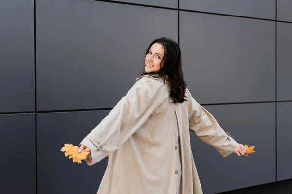 Morena Mujer Impermeable Beige Sonriendo Cámara Mientras Posa Con Follaje — Foto de Stock