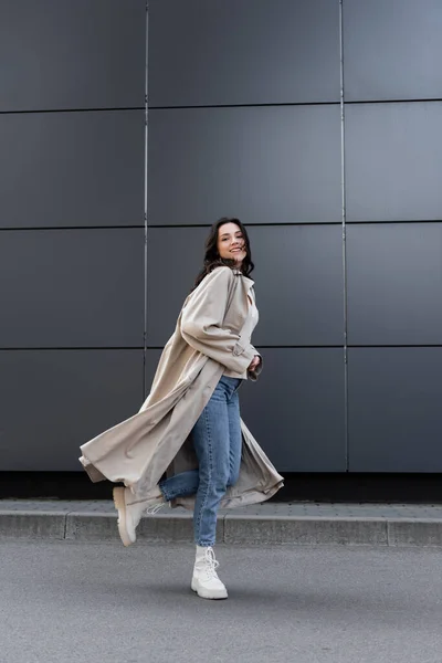 Mujer Sonriente Jeans Botas Blancas Impermeable Largo Corriendo Largo Pared — Foto de Stock