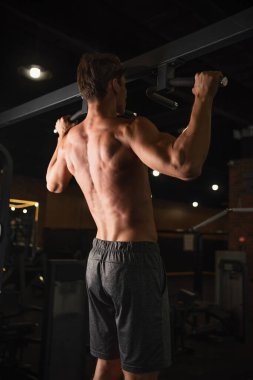 Spor merkezindeki yatay barda üstsüz atletizm eğitiminin arka görüntüsü