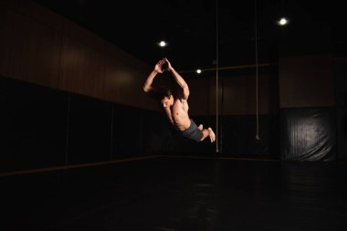 Spor salonunda çıplak ayak ve üstsüz jimnastikçi atlarken