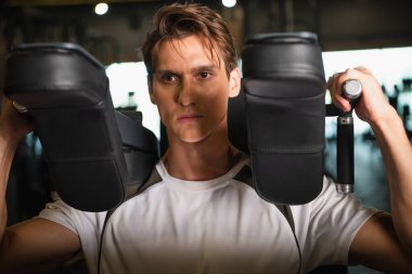 Spor salonunda kollarını uzatma egzersizi üzerine yoğunlaştırılmış spor eğitimi.