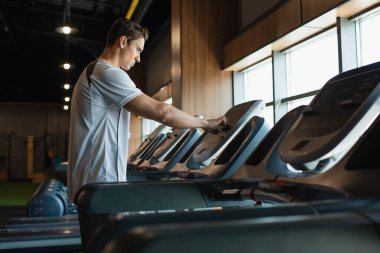 spor adamı bulanık önplanda koşu bandında dokunmatik ekran kullanıyor