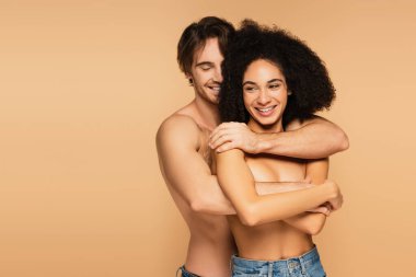 Gülümseyen üstsüz adam üstsüz ve mutlu İspanyol kadın bej rengi giyinmiş.