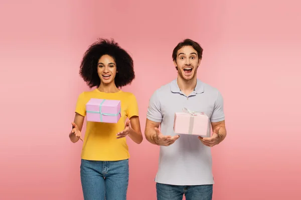 Amazed Multiethnic Couple Looking Camera Flying Gift Boxes Isolated Pink — Stock Photo, Image