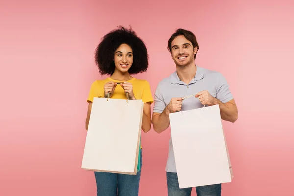 Young Happy Interracial Couple Standing Shopping Bags Isolated Pink — Stock Photo, Image