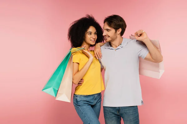 Happy Interracial Couple Shopping Bags Looking Each Other Isolated Pink — Stock Photo, Image