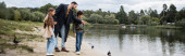 Arabský rodič ukazuje na jezero poblíž dětí v parku, prapor 