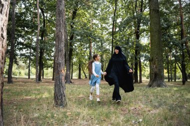 Parkta el ele tutuşan pozitif Arap anne ve kızı 