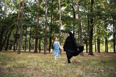 Müslüman anne ve çocuk parkta oynarken koşuyorlar 