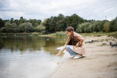 Park 'taki gölü gösteren Müslüman kızın yan görüntüsü
