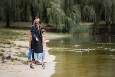 Parktaki plajda ailesinin yanında duran Arap bir adam. 