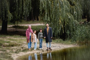 Park 'taki gölün yakınındaki kameraya gülümseyen Arap ailesi 