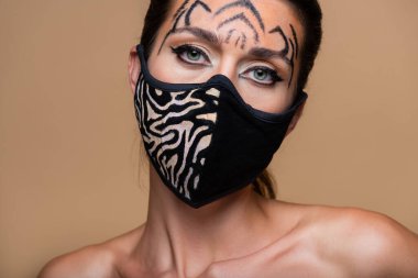Kaplan makyajlı ve hayvan desenli maskeli genç bir model bej rengi elbisenin üzerine izole edilmiş.