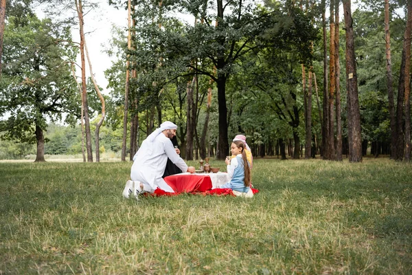 Positivo Pai Árabe Sentado Perto Família Durante Piquenique Parque — Fotografia de Stock