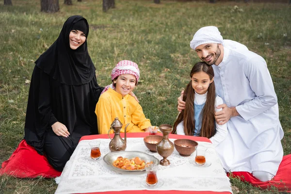 Sorrindo Pais Árabes Abraçando Crianças Perto Comida Chá Parque — Fotografia de Stock