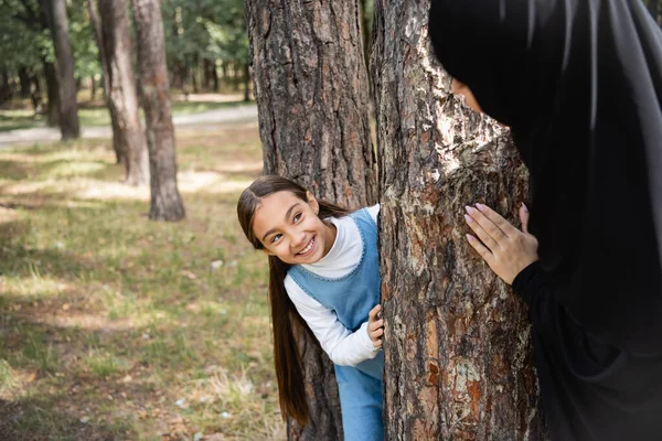 Leende Arabiska Flicka Tittar Suddig Mor Nära Träd Utomhus — Stockfoto