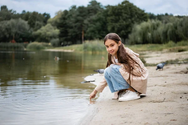 Arabian girl looking at camera near lake in park