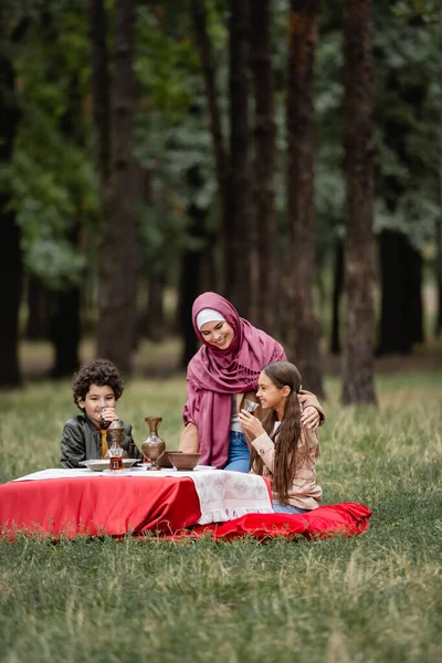 Usmívající Děti Holing Čaj Brýlích Poblíž Muslimské Matky Hidžábu Parku — Stock fotografie