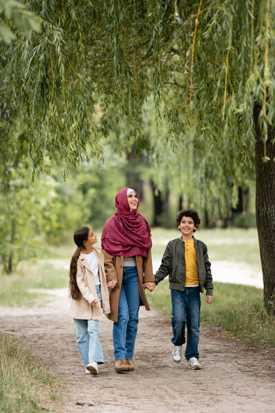 Arabian family walking under willow tree in park 