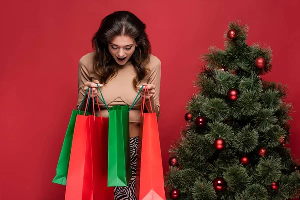 Mujer Joven Sorprendida Sosteniendo Bolsas Compras Cerca Del Árbol Navidad — Foto de Stock