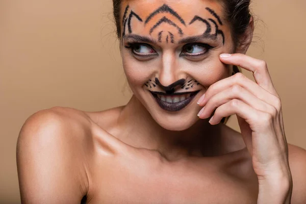 stock image joyful young woman with bare shoulders and tiger makeup posing isolated on beige