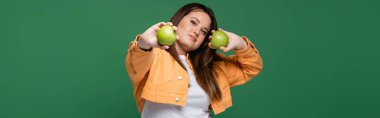 Yeşil elmaları yeşil pankartta saklayan şişman güzel bir kadın. 