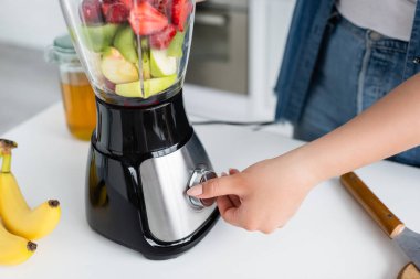 Mutfakta smoothie pişirirken büyük beden kadın blender değiştiriyor. 