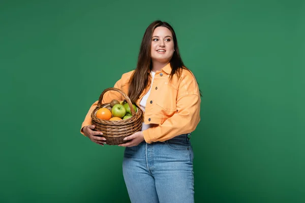 Lächelnde Frau Mit Übergewichtigem Körbchen Mit Früchten Auf Grünem Grund — Stockfoto