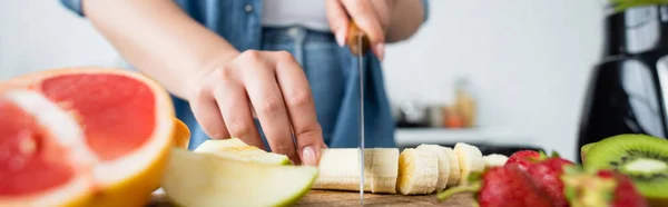 Vista Recortada Mujer Cortando Plátano Cerca Frutas Borrosas Cocina Pancarta — Foto de Stock