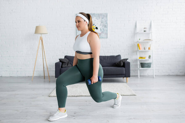 Brunette woman with overweight doing lunges with dumbbell at home 